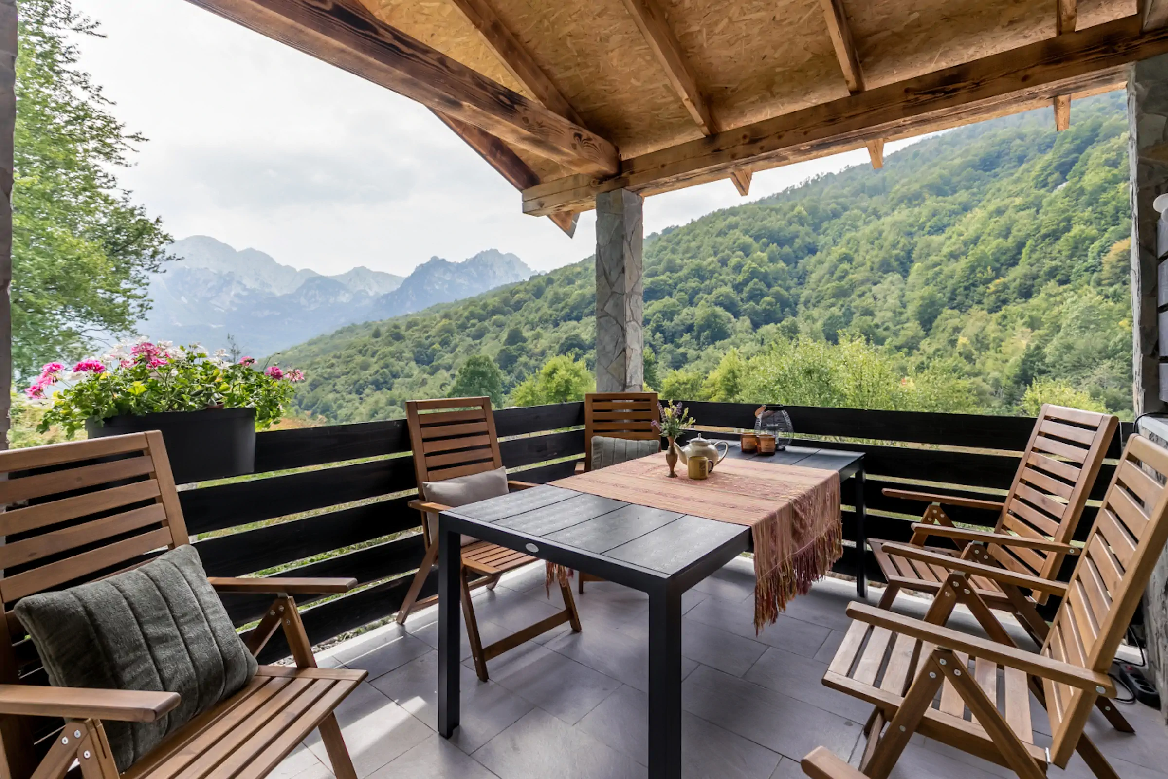 Covered outdoor terrace with wooden furniture and dramatic Montenegro mountain peaks views from Fireside Lodge