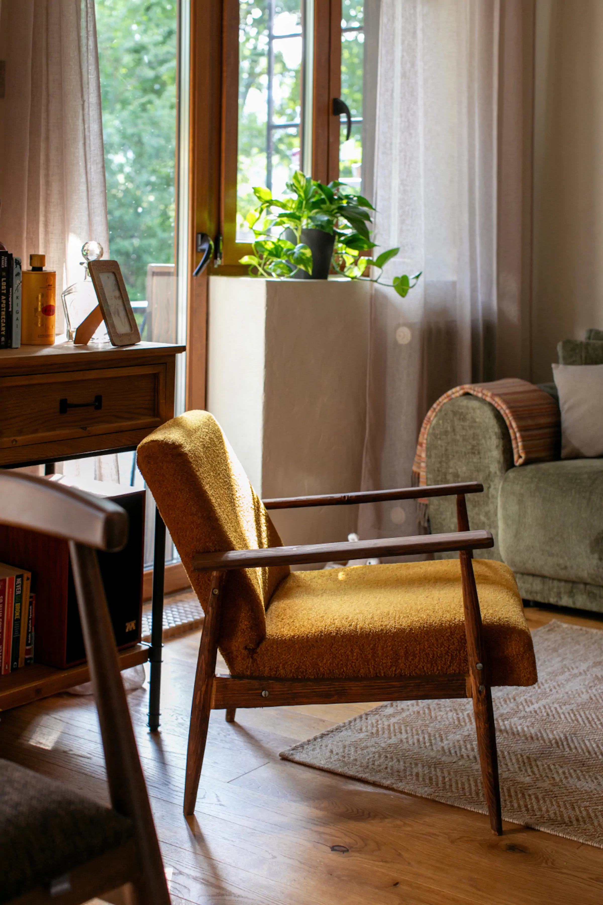 Iconic mustard yellow mid-century modern armchair with wooden frame in sunlit living room at Fireside Lodge Montenegro
